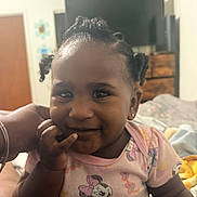 Melia Bloom joined the competition — help win amazing prizes! baby, child, infant, smiling, portrait, indoors, bedroom, bed, television, dresser, adult_hand, curly_hair, braids, earring, pink_clothing, onesie, minnie_mouse, cartoon, sitting, family