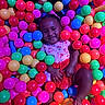 Melia Bloom is registered to the contest to win money with this photo: child, toddler, girl, smiling, portrait, ball_pit, colorful_balls, playground, indoor, sitting, happy, face, person, pink_clothing, red_skirt, hair_bow, playtime, recreation, bright_colors, photography
