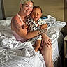 Terrance is registered to the contest to win money with this photo: bed, blanket, bracelet, child, family, footwear, furniture, happy, headboard, holding, indoor, necklace, pajamas, person, portrait, skin, smiling, tattoos, white_bedding, woman