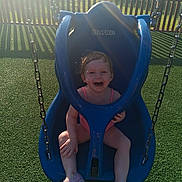 Riley is registered to the contest to win money with this photo: toddler, child, swing, playground, outdoor, smiling, joyful, blue, sunlight, grass, fence, park, summer, happy, seat, plastic, play, fun, person, casual