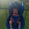 toddler, child, swing, playground, outdoor, smiling, joyful, blue, sunlight, grass, fence, park, summer, happy, seat, plastic, play, fun, person, casual