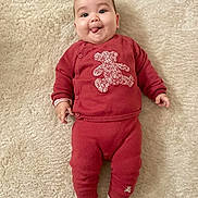 Livia a rejoint le concours — aidez-le/la à gagner de superbes lots ! baby, infant, red_clothing, teddy_bear_patch, lying_down, carpet, tongue_out, cute, child, smiling, happy, cozy, sock, playful, portrait, indoors, soft_texture, head, face, person