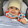 baby, child, infant, hat, knit_hat, pom_poms, bib, animal_print, tongue_out, cute, smiling, stroller, blanket, cozy, clothing, face, hand, happy, indoors, portrait