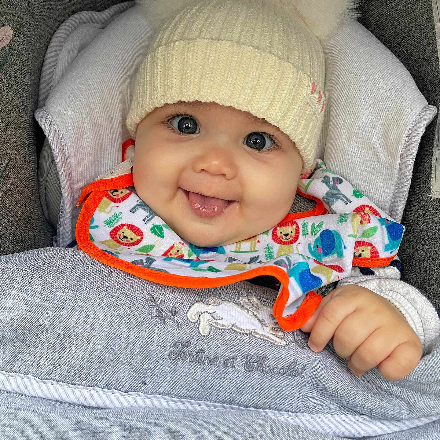 Livia participe au concours pour gagner de l'argent avec cette photo : animal_print, baby, bib, blanket, child, clothing, cozy, cute, face, hand, happy, hat, indoors, infant, knit_hat, pom_poms, portrait, smiling, stroller, tongue_out