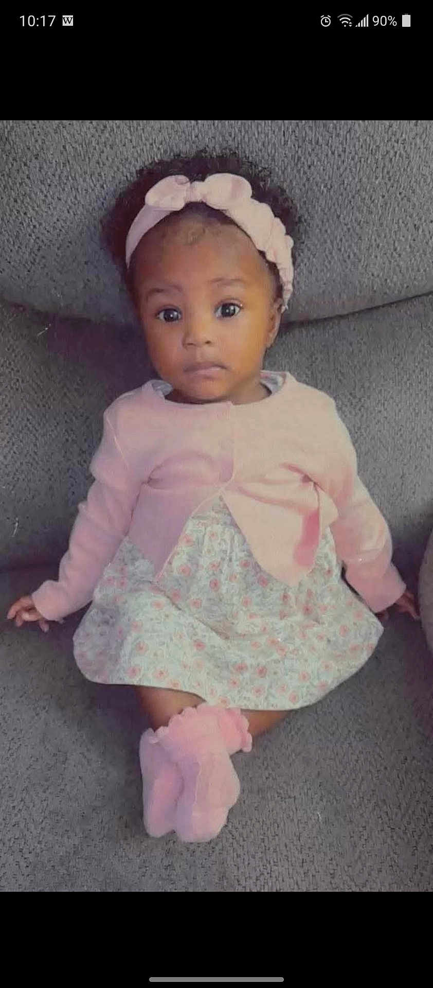 Lahretta is registered to the contest to win money with this photo: baby, child, infant, girl, pink_headband, pink_cardigan, floral_dress, pink_socks, sitting, couch, gray_couch, indoor, portrait, curious_expression, wide_eyes, headband, cozy, cute, toddler, person