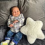 baby, plaid_shirt, jeans, socks, couch, pillow, star_shaped_pillow, gray_couch, infant, child, indoors, fabric, soft_toy, cute, portrait, young_child, seated, expression, home, cozy
