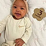 baby, infant, smiling, headband, bow, beige_clothing, onesie, wooden_sign, 3_months, blanket, pink_bows, lying_down, cute, happy, portrait, closeup, child, person, indoors, soft_lighting