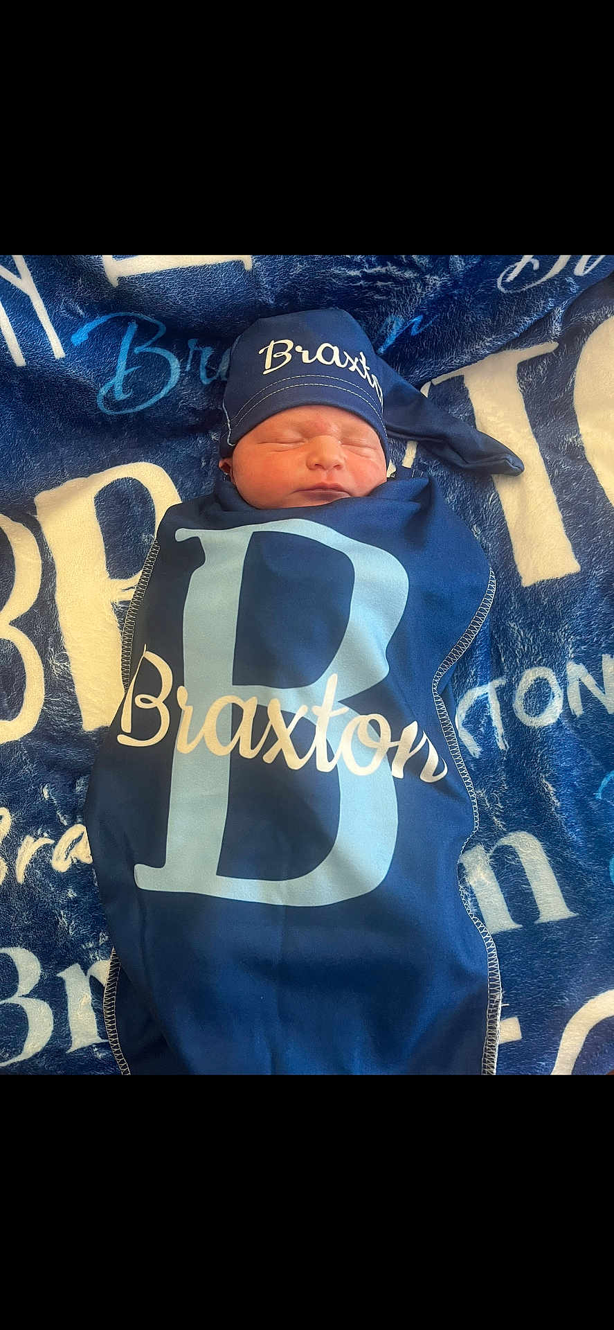 Braxton is registered to the contest to win money with this photo: newborn, baby, sleeping, blanket, hat, personalized, navy_blue, cozy, soft, wrapped, infant, child, resting, text, pattern, fabric, portrait, cute, peaceful, indoors