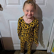 Bexley is registered to the contest to win money with this photo: child, girl, sunflower, outfit, pattern, yellow, flower, hair_clip, smile, standing, door, carpet, shoes, daisy, indoor, happy, cute, fashion, portrait, playful