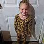 child, girl, sunflower, outfit, pattern, yellow, flower, hair_clip, smile, standing, door, carpet, shoes, daisy, indoor, happy, cute, fashion, portrait, playful