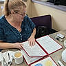 Arlo Little Button joined the competition — help win amazing prizes! woman, glasses, pony_tail, menu, dog, black_dog, chair, table, coffee, cup, spoon, fork, napkin, keys, window, indoor, restaurant, food_menu, person, casual