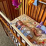 baby, crib, sleeping, plush_toys, quilted_blanket, wooden_furniture, carpet, onesie, indoor, child, infant, peaceful, colorful, toy, bedroom, rest, cute, soft, naptime, cozy