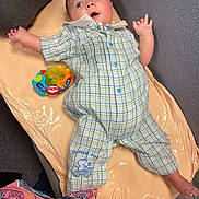 Levi is registered to the contest to win money with this photo: baby, infant, plaid_onesie, toy, changing_mat, floor, carpet, colorful_toy, patterned_clothing, child, indoor, cute, lying_down, expression, blue_eyes, short_hair, foot, hand, fabric, comfort