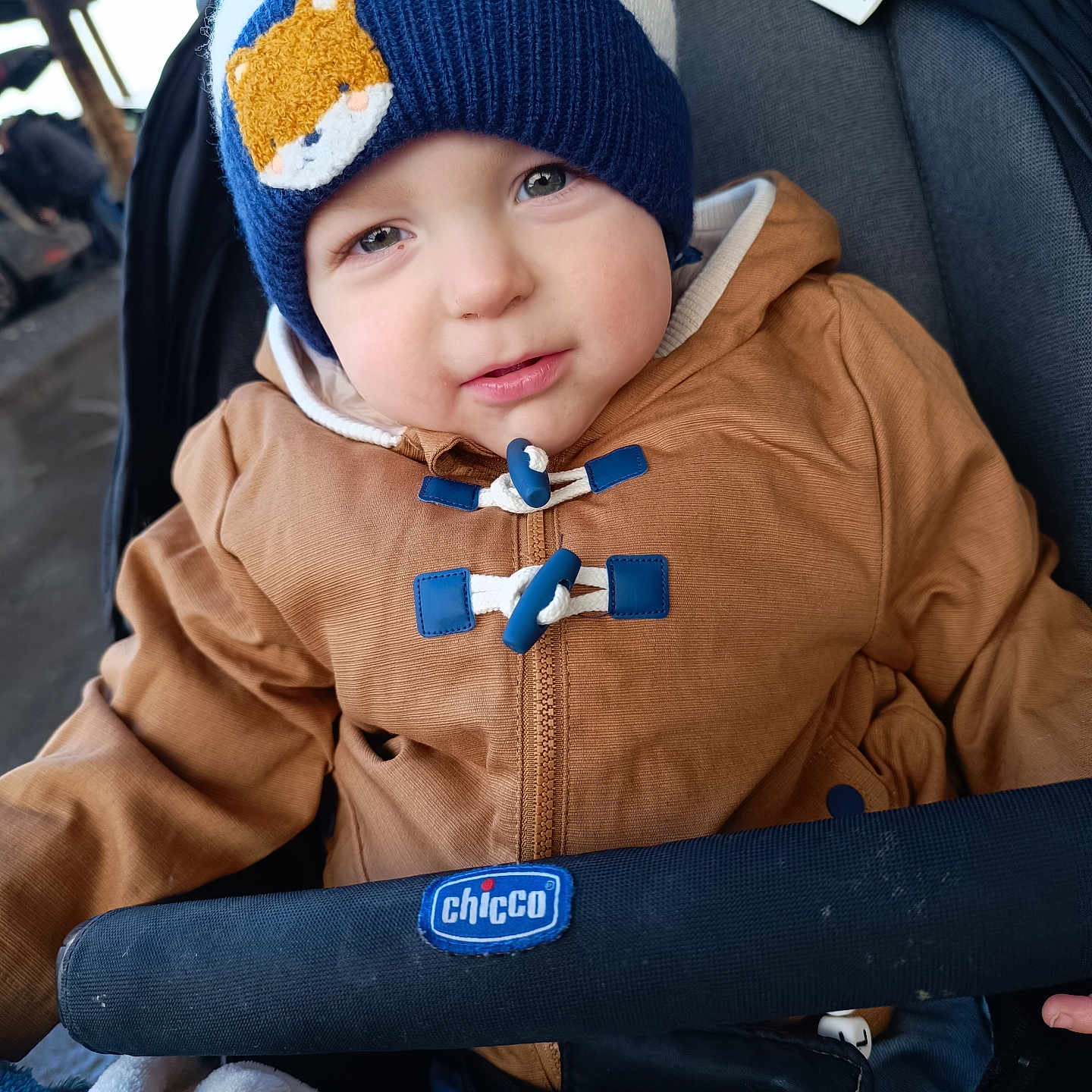 Maël a rejoint le concours — aidez-le/la à gagner de superbes lots ! baby, baby_stroller, bear_patch, blanket, blue, brown_jacket, child, cute, face, hat, jacket, knit_hat, outdoor, person, portrait, seated, stroller, toddler, white, winter_clothing