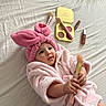 baby, bathrobe, beauty, bed, bedding, blush, bunny_headband, child, cosmetics, cute, eyeshadow, hands, indoor, infant, lying_down, makeup, makeup_brush, pink, portrait, smiling