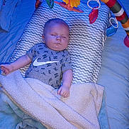 Braxton is registered to the contest to win money with this photo: baby, sleeping, blanket, pillow, toy, colorful, infant, bed, soft, cozy, child, cute, rest, peaceful, indoors, clothing, tshirt, pattern, blue_light, comfort