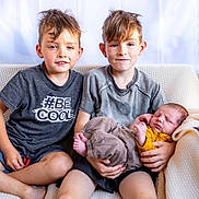 Owenn participe au concours pour gagner de l'argent avec cette photo : baby, barefoot, blanket, blond_hair, casual_clothing, child, couch, cute, family, happy, holding, indoor, portrait, relaxing, seated, short_hair, siblings, smiling, toddler, young