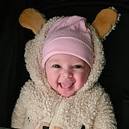 Ania participe au concours pour gagner de l'argent avec cette photo : apparel, baby, bear_costume, child, closeup, costume, cute, dark_background, ears, expression, face, fluffy, happy, hat, infant, pink_hat, portrait, smiling, tongue_out, warm_clothing