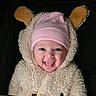 apparel, baby, bear_costume, child, closeup, costume, cute, dark_background, ears, expression, face, fluffy, happy, hat, infant, pink_hat, portrait, smiling, tongue_out, warm_clothing