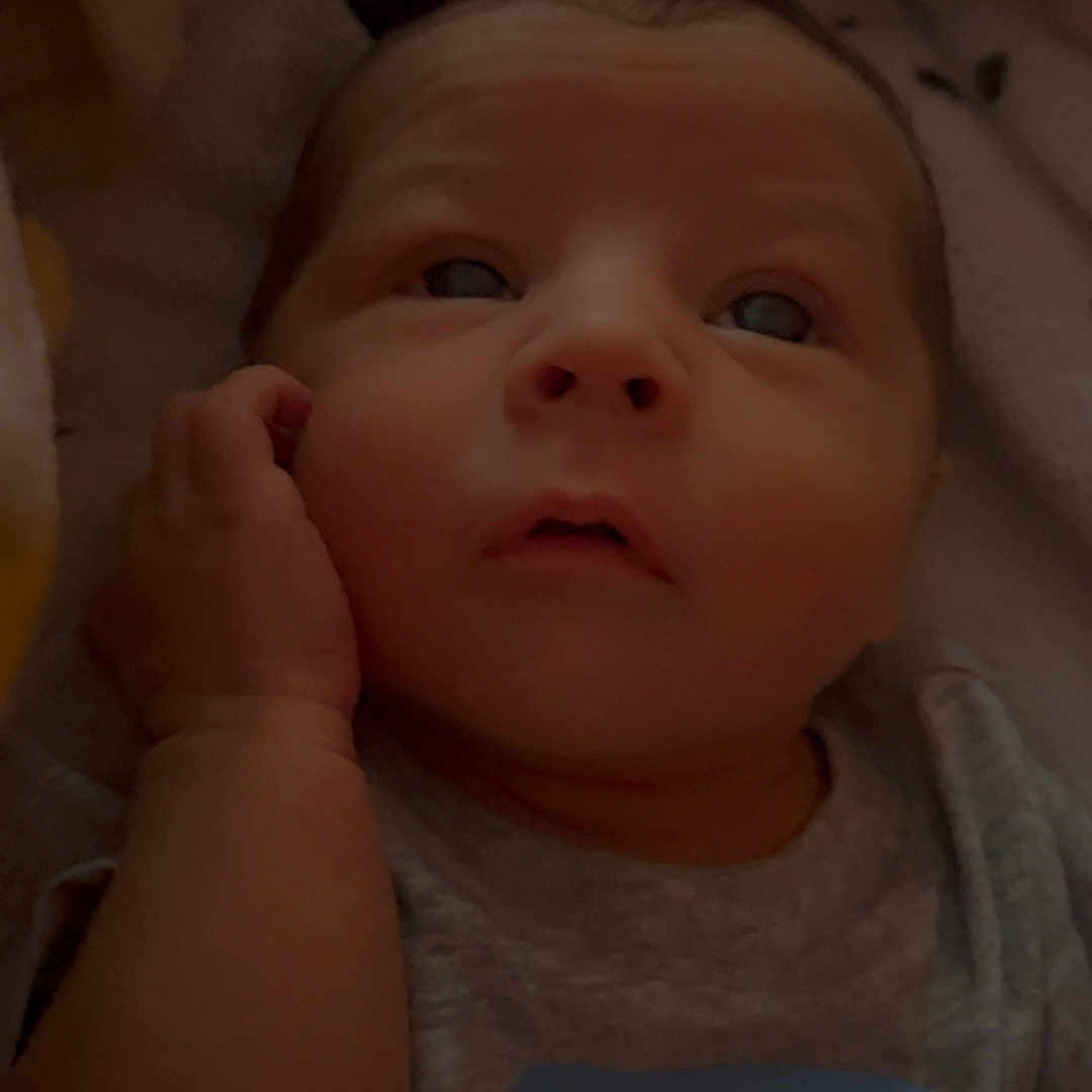 Kingston is registered to the contest to win money with this photo: baby, newborn, infant, child, face, hand, shirt, text, blanket, sleepwear, cute, portrait, expression, resting, eyes, skin, head, lying_down, indoors, soft_lighting
