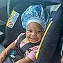 baby, car_seat, smile, bonnet, pacifier, child, pink_shirt, safety_harness, infant, happy, cute, indoor, seatbelt, portrait, child_in_car_seat, clothing, face, person, seat, car_interior