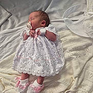 Georgia is registered to the contest to win money with this photo: newborn, baby, sleeping, pacifier, white_dress, lace, pink_booties, blanket, knitwear, infant, cute, peaceful, indoors, soft_lighting, portrait, closeup, resting, small_hands, cozy, delicate