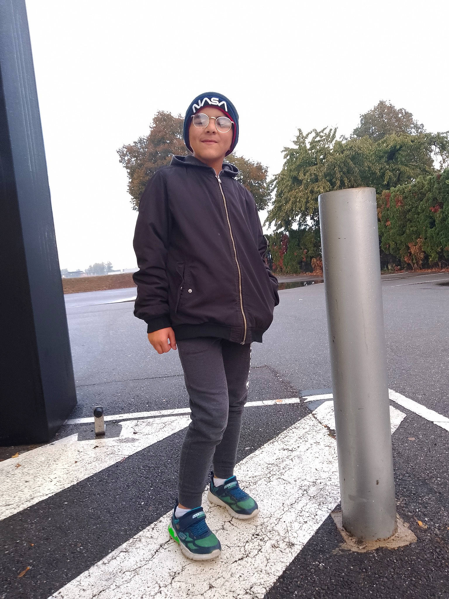 Marion participe au concours pour gagner de l'argent avec cette photo : asphalt, electric_blue, eyewear, fashion_accessory, footwear, headwear, human_leg, jacket, leg, leisure, pedestrian, person, plant, recreation, road, road_surface, sky, sneakers, standing, tints_and_shades