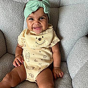 Faith joined the competition — help win amazing prizes! baby, child, smile, headband, onesie, bib, armchair, indoor, portrait, happy, cute, infant, person, seated, clothing, texture, furniture, face, skin, hand