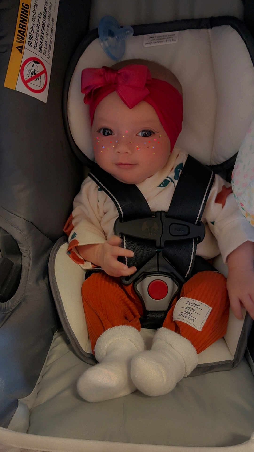 Pheonix is registered to the contest to win money with this photo: baby, car_seat, headband, pink, freckles_filter, clothing, straps, socks, infant, cute, portrait, indoor, child, seat_belt, warning_label, hands, face, eyes, expression, cozy