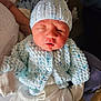 William is registered to the contest to win money with this photo: newborn, baby, knit_hat, knit_cardigan, sleepy, infant, person, clothing, white_outfit, handheld, soft_lighting, indoor, cute, tiny, sleeping, portrait, closeup, warm, cozy, human