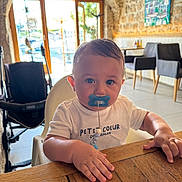 Nahyl a rejoint le concours — aidez-le/la à gagner de superbes lots ! baby, child, pacifier, highchair, wooden_table, indoor, cafe, stone_wall, window, daylight, white_shirt, blue_pacifier, face, hands, chair, stroller, furniture, portrait, cute, toddler