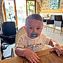 baby, child, pacifier, highchair, wooden_table, indoor, cafe, stone_wall, window, daylight, white_shirt, blue_pacifier, face, hands, chair, stroller, furniture, portrait, cute, toddler