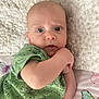 Stefan is registered to the contest to win money with this photo: baby, infant, child, green_shirt, dinosaur_print, blanket, butterfly_pattern, bed, curious_expression, wide_eyes, lying_down, pale_skin, indoors, textured_blanket, close_up, portrait, hand_near_face, soft_lighting, comfortable, casual_clothing