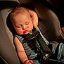 baby, sleeping, car_seat, child, infant, blue_clothing, striped_clothing, seatbelt, safety_harness, cute, peaceful, relaxed, chubby_cheeks, indoor, portrait, one_arm_up, resting, person, soft_lighting, comfort