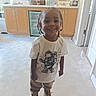 Zion joined the competition — help win amazing prizes! child, toddler, smiling, portrait, braids, kitchen, indoors, standing, t_shirt, bear_graphic, pants, boots, wooden_cabinets, countertop, sink, bathroom_products, tile_floor, home, happy, full_body