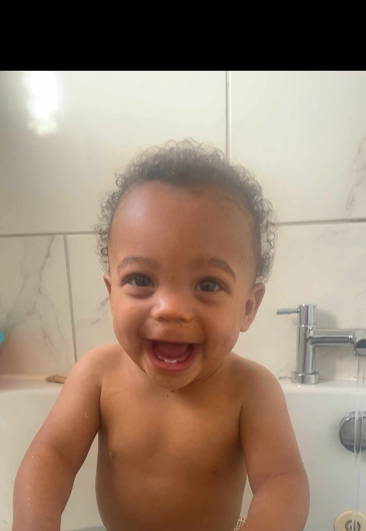 Kayden joined the competition — help win amazing prizes! toddler, child, bathroom, bathtub, water, curly_hair, smiling, happy, naked, faucet, tiles, skin, face, teeth, playful, young_child, indoor, water_flow, person, joy