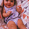 baby, child, smiling, happy, ponytails, patterned_blanket, geometric_pattern, purple_dress, infant, cute, play_text, indoors, portrait, face, skin, legs, feet, hand, young, sitting