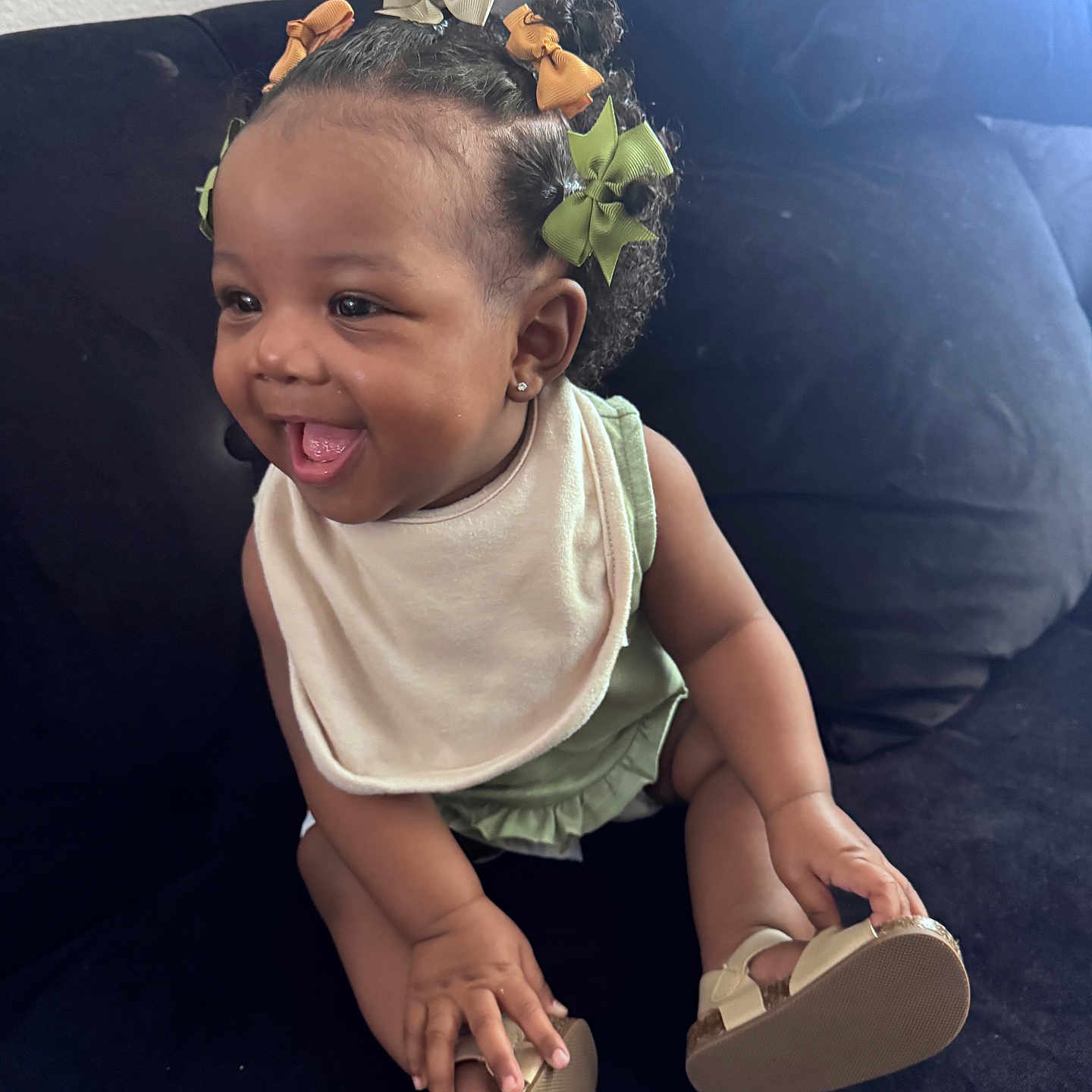 Azai is registered to the contest to win money with this photo: baby, bib, child, clothing, couch, cute, footwear, hair_bows, hand, happy, indoors, infant, person, playful, portrait, shoes, sitting, skin, smiling, young