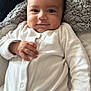 Ibrahim joined the competition — help win amazing prizes! baby, infant, smiling, white_onesie, hand, face, pillow, soft_texture, indoor, cute, child, young, portrait, comfort, relaxed, person, cozy, skin, head, expression