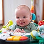 baby, smiling, child, infant, toy, activity_center, colorful, happy, playful, indoor, person, clothing, seat, cute, young, hands, face, head, expression, early_childhood