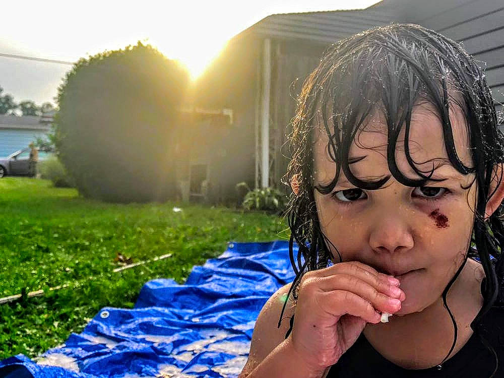 Elia is registered to the contest to win money with this photo: beauty, black_hair, child, cool, fun, gesture, glasses, grass, hairstyle, happy, human, mouth, nose, person, photography, plant, sitting, smile, summer, sunlight