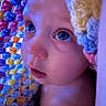 baby, child, face, blue_eyes, blanket, crocheted_blanket, colorful, close_up, skin, soft_light, portrait, expression, curious, indoors, newborn, infant, head, eyelashes, nostrils, cheeks