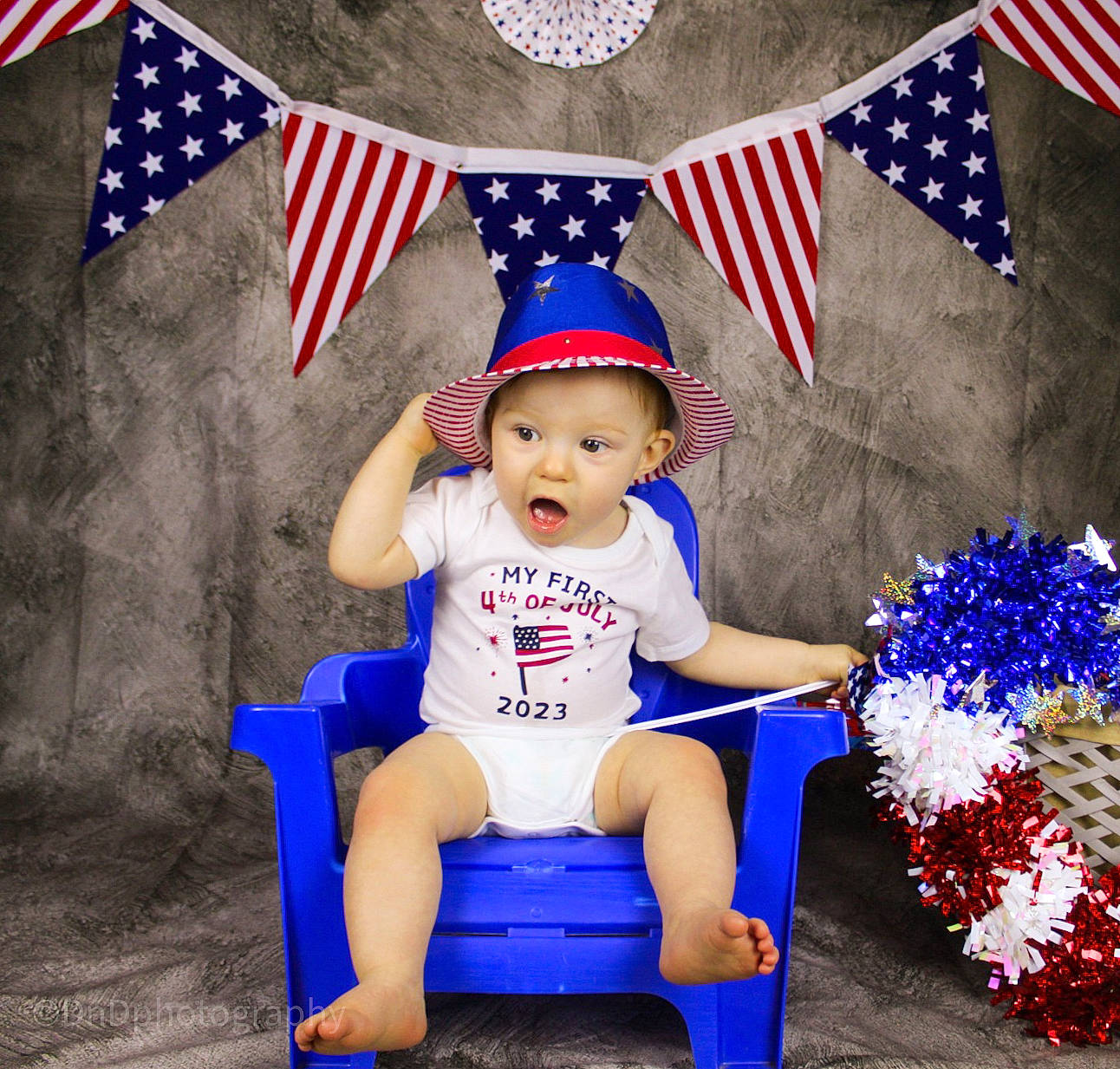 Dawson is registered to the contest to win money with this photo: baby_toddler_clothing, blue, cap, costume_hat, electric_blue, event, flag, flag_day_usa, flag_of_the_united_states, happy, hat, headwear, holiday, person, photograph, sitting, sports_uniform, surprise, t_shirt, thigh
