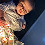 baby, child, blanket, lights, christmas_lights, santa_claus, indoors, soft_lighting, curious, infant, portrait, warm_light, cozy, face, person, holiday, decorations, wrapped, young_child, closeup
