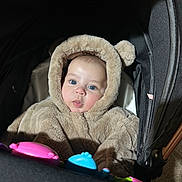 Noah Cristian joined the competition — help win amazing prizes! baby, child, stroller, fuzzy_clothing, hood, toy, blue_eyes, cute, infant, portrait, indoor, warm_clothing, pink, blue, black, face, person, soft_texture, animal_ears, curious