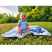Liam joined the competition — help win amazing prizes! baby, blanket, blue_clothing, child, cute, daylight, grass, greenery, happy, infant, nature, octopus, outdoor, park, playtime, plush, sitting, smiling, sunlight, toy