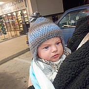 Liam is registered to the contest to win money with this photo: baby, blanket, blue_eyes, child, cold_weather, convenience_store, curious, face, fuzzy_jacket, hat, holding, jacket, knit_hat, night, outdoor, person, pom_pom, storefront, van, vehicle