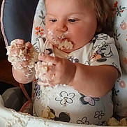 Oakley is registered to the contest to win money with this photo: baby, child, high_chair, messy, cake, frosting, food, hands, face, cute, infant, eating, fun, expression, clothing, indoor, person, seat, playful, smudged