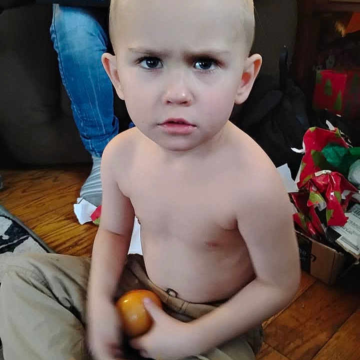 Jordan is registered to the contest to win money with this photo: box, casual, child, curious, expression, face, floor, furniture, home, indoors, jeans, living_room, person, shirtless, sitting, toddler, toy, wooden_floor, wrapping_paper, young