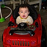 baby, child, toy_car, indoor, surprised_expression, striped_clothing, flooring, chair, table, plastic_toys, furniture, playroom, head, face, person, seat, footwear, expression, young_child, playtime